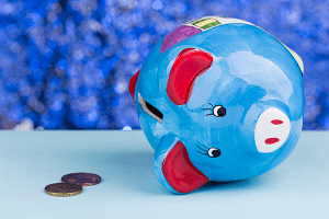 blue piggy bank on its side with two pennies on a table